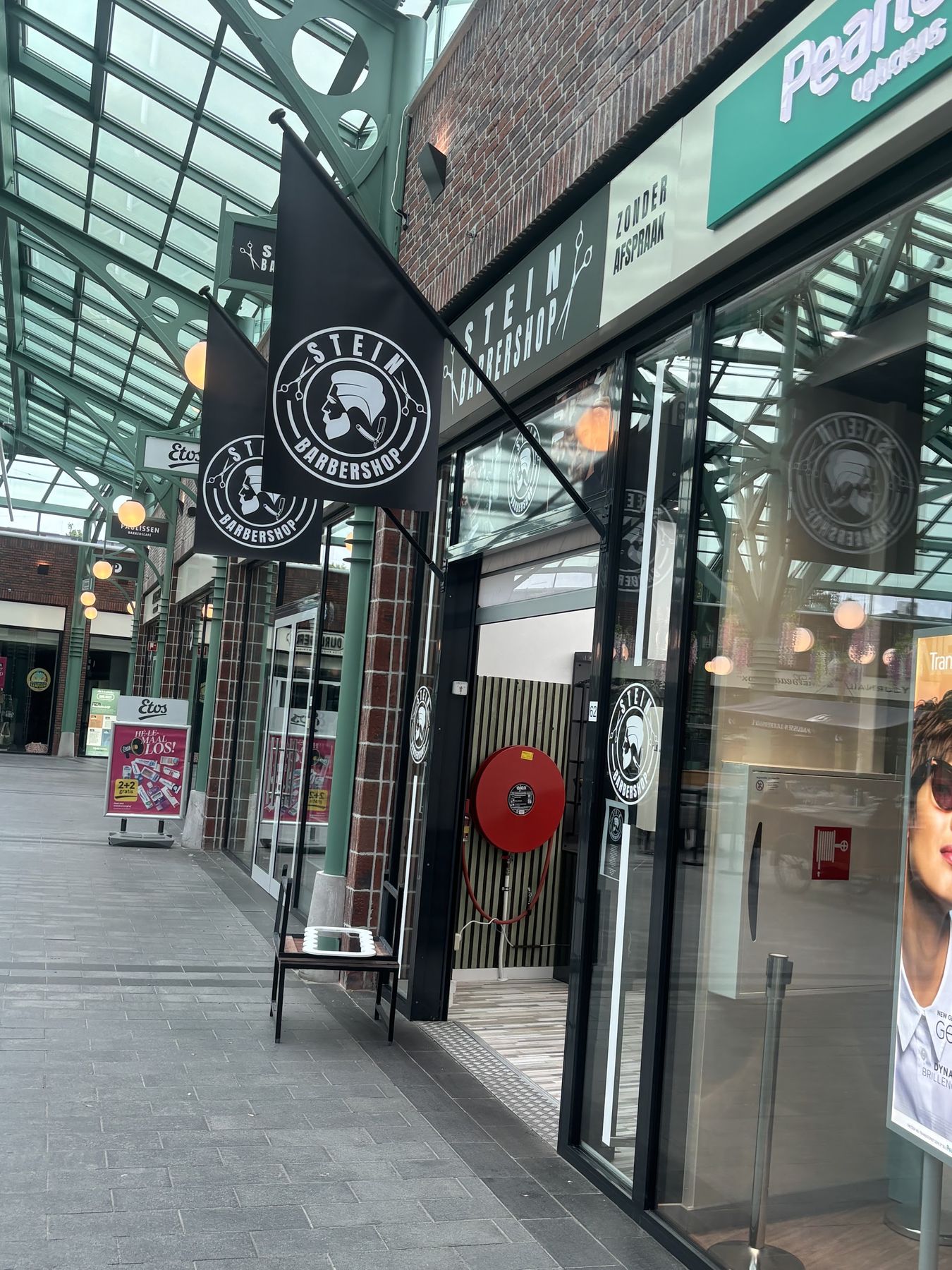 De winkelpui van Stein Barbershop in Winkelcentrum Stein, met de vlag en Zonder afspraak op het raam
