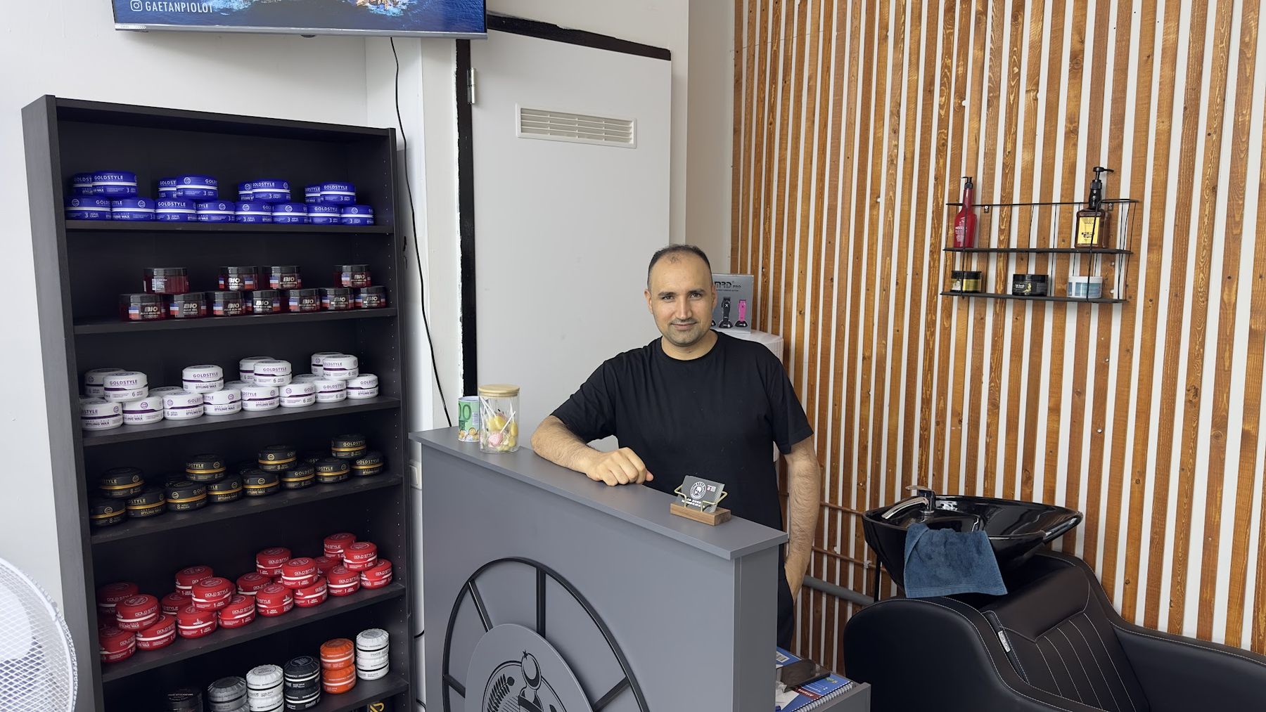 De eigenaar bij de balie naast een wand vol haarproducten